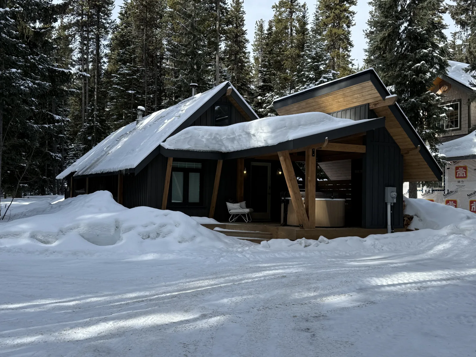 Snow-covered front exterior of 1166 Apex Mountain Road in Penticton, surrounded by evergreen trees.