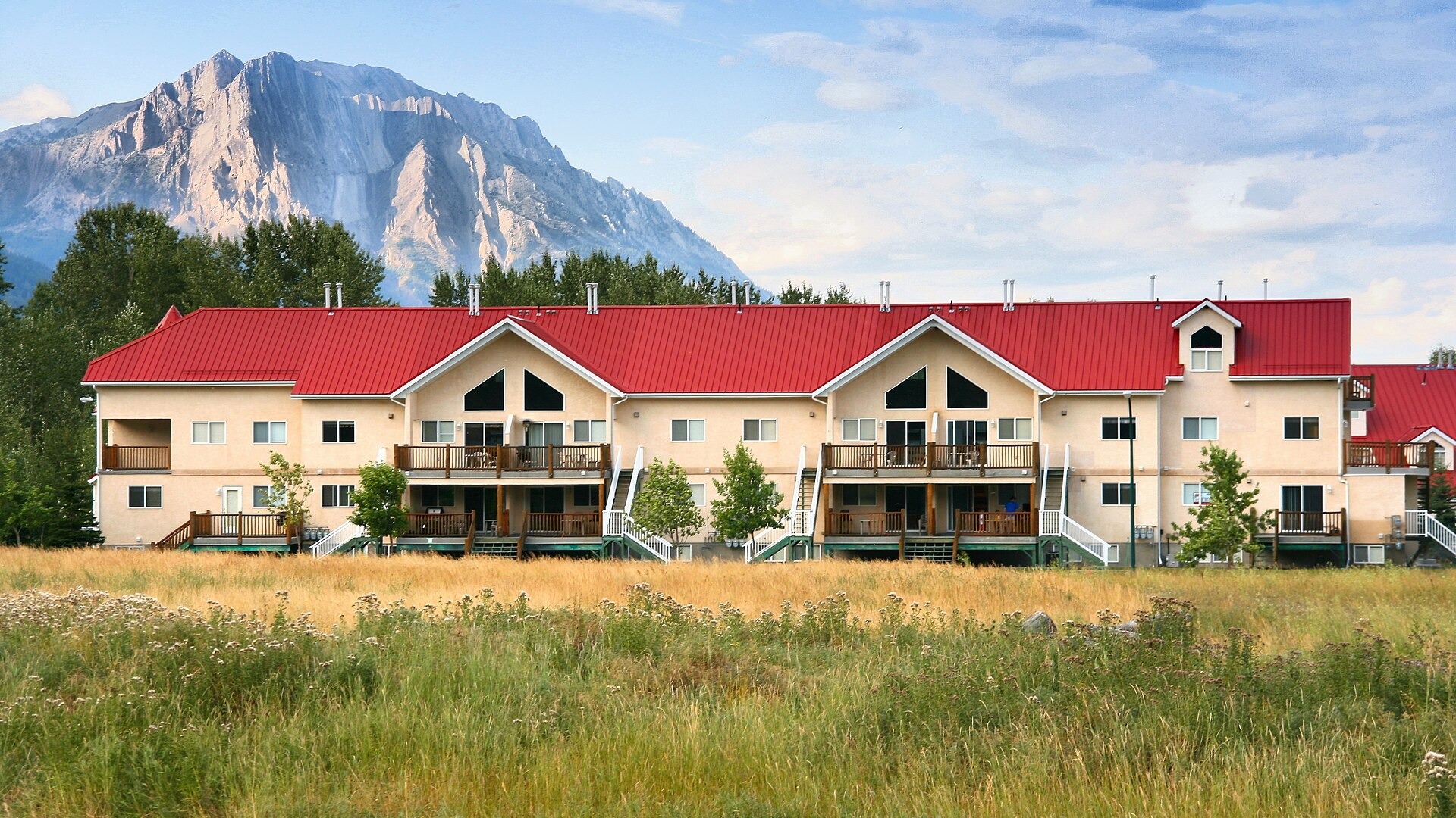 Low-rise condominium building with balconies, a red roof and a mountain behind it in Fernie, British Columbia