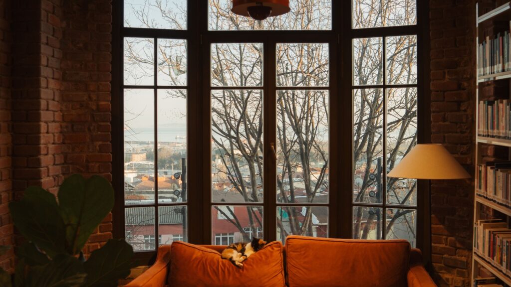 Orange sofa in a brick living room beside a large multi-pane exterior window
