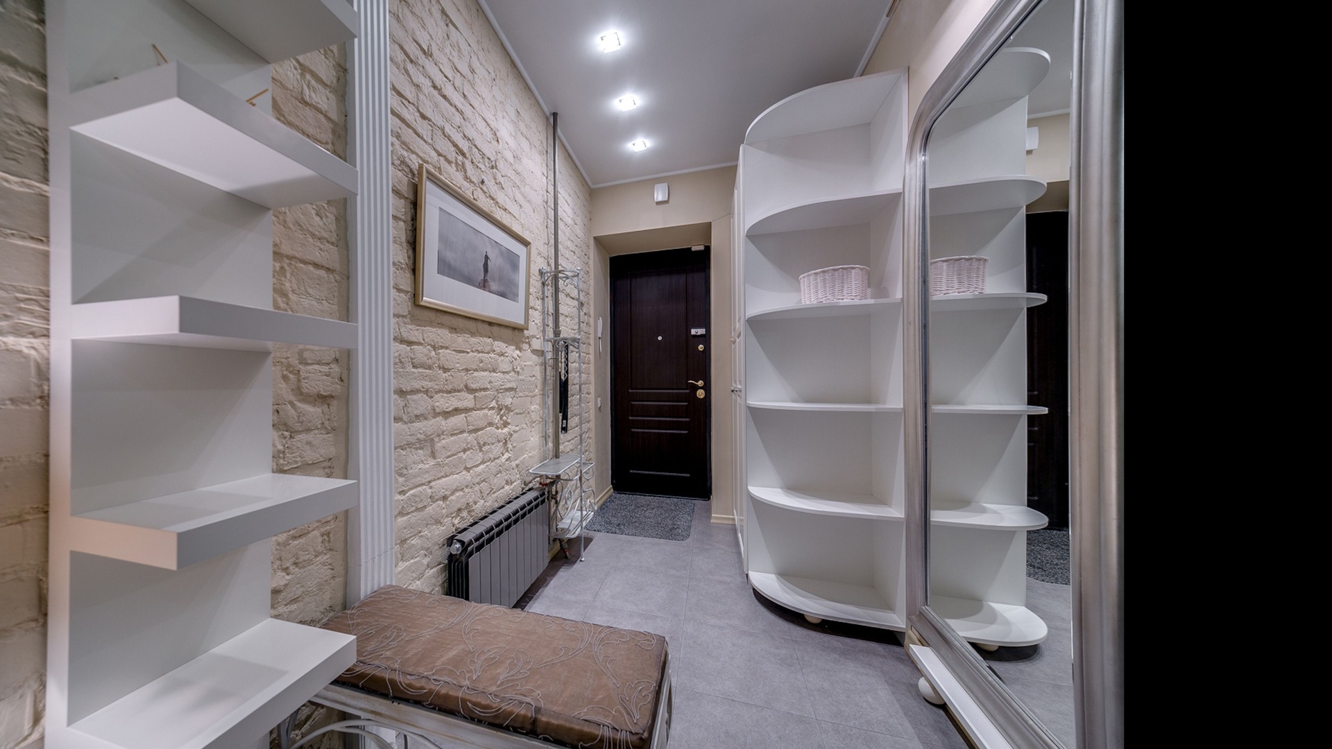 Entry hall with dark exterior door, white shelving, mirrored wardrobe and bench