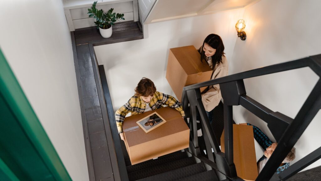 Family carrying moving boxes up an indoor staircase