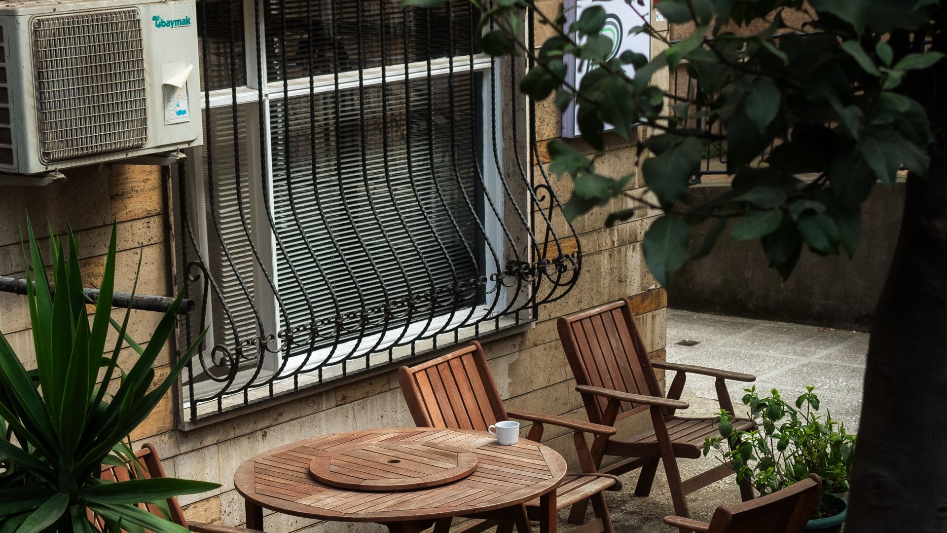 Small urban patio with wooden table and chairs below neighbouring windows