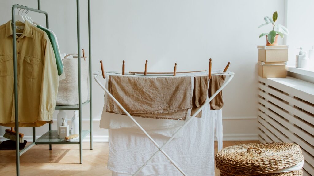 Wicker laundry basket beside clothes drying in a sunlit room