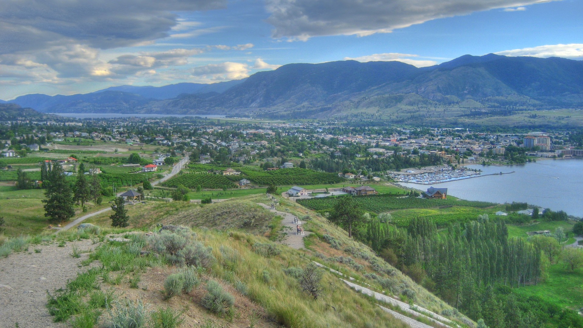 Panoramic view of Penticton homes, orchards, marina, Okanagan Lake and surrounding mountains from Munson Mountain Park